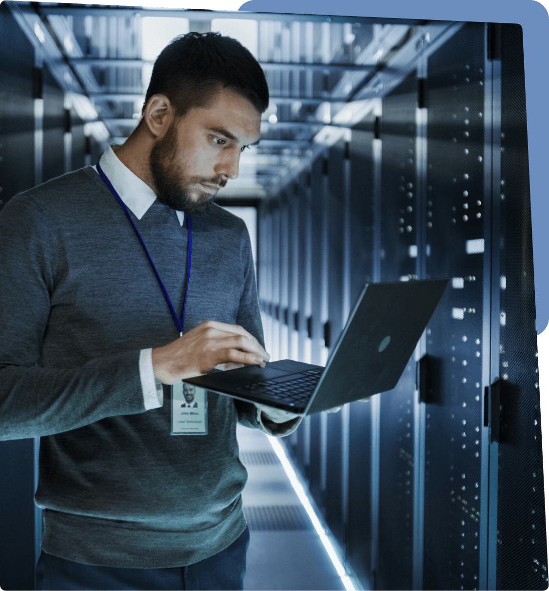 Man working on laptop in server room.