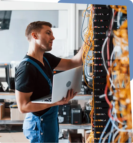 Technician working on server rack with laptop.